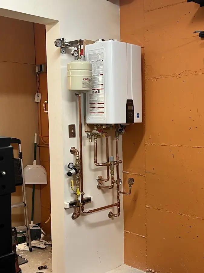 Plumbing technician inspecting water heater connections in Edinburgh